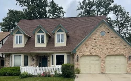 Exterior painting by Slaviks Painting & Decorating in Wood Dale, IL. The image shows a tan stone home with cream garage doors.