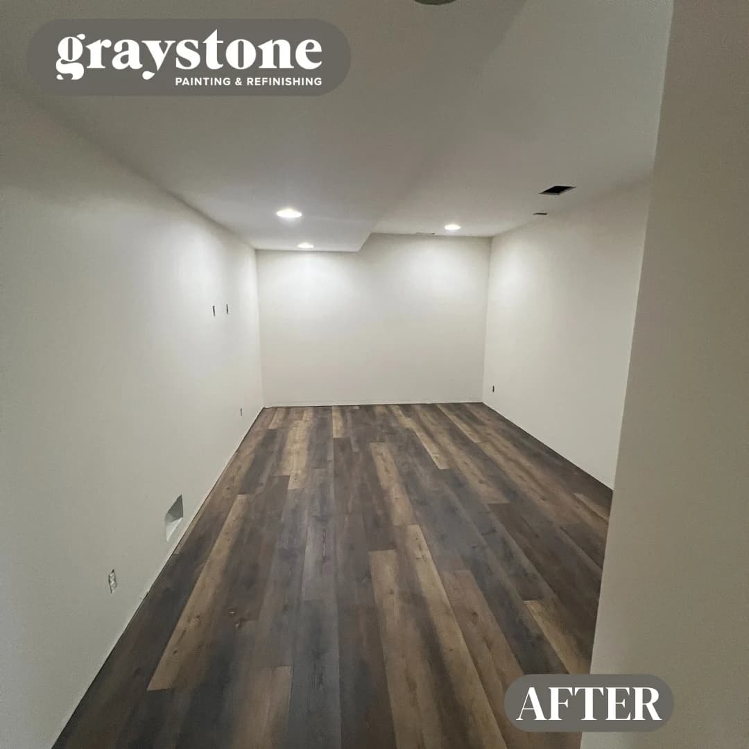 This is an image from Graystone Painting and Refinishing. The image is an interior room in Kansas City KS with newly painted light walls and dark wood-look flooring.