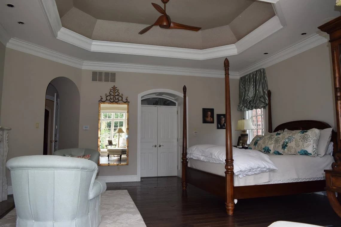 Interior painting project by Premier Painting and Design Inc. in Collinsville, Illinois. The image shows neutral walls, white crown molding, a tray ceiling, and dark flooring.