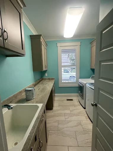 Interior painting project by Avanti Painting LLC in Mooresville, NC. The image shows a teal utility room with cabinets, sink, and washer.