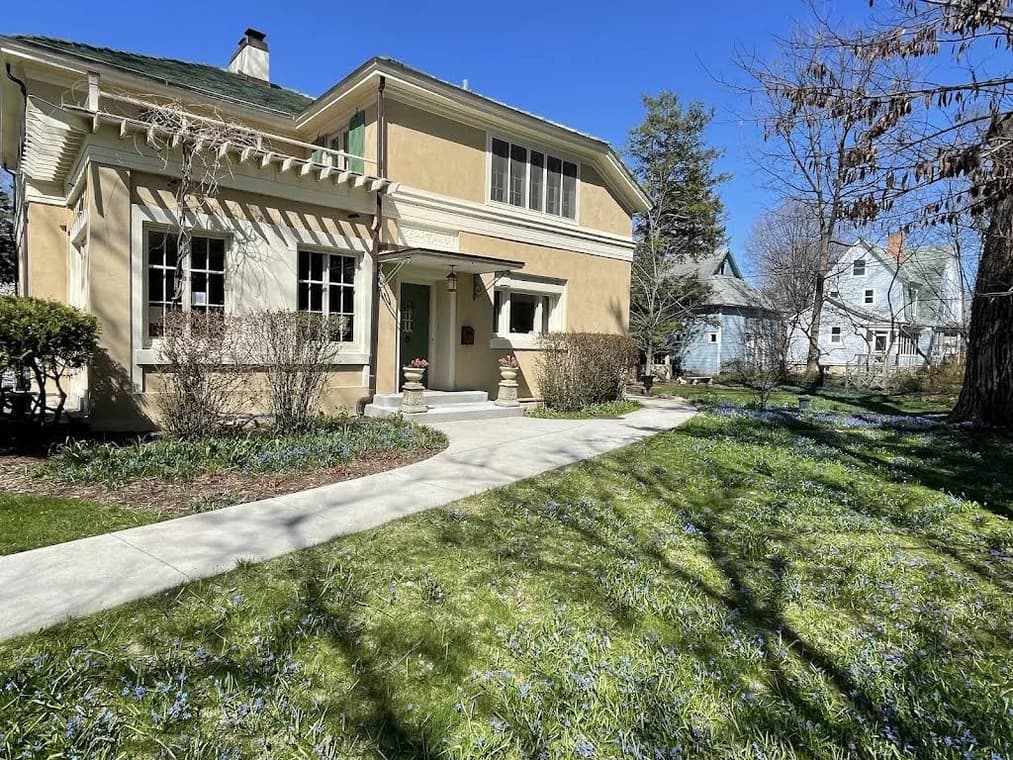 Exterior stucco project by JJ Stucco & Plastering System Inc. in Lake in the Hills, Illinois. The image shows a tan home with striped awnings and a front walkway.