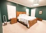 Interior painting project by CertaPro Painters of Durham, NC in Durham, NC. The image shows teal bedroom walls, white trim, wood furniture, and a patterned rug.