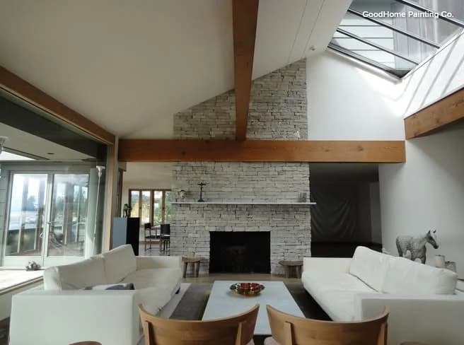 This is an image from DABS Painting, located in Texas. The image shows a modern living room with white painted walls, exposed wood beams, and a stone fireplace.