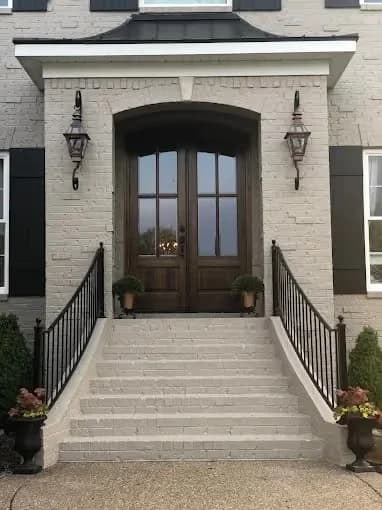 Painting work by Nashville Painting Company - Brentwood in Brentwood, Tennessee. The image shows a light brick entry with dark double doors.