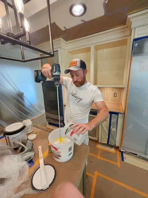 This is an image from Aluisy & Company, Inc. company, located in Stewartstown, PA,. The image is a painter mixing cabinet paint for a kitchen renovation.
