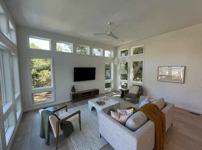 Interior painting project by Kitty Hawk Painting in Kitty Hawk, NC. The image shows a living room with tall windows, white walls, and light flooring.