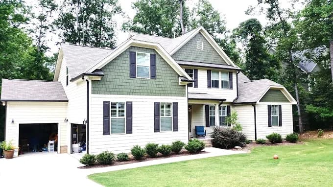 Exterior painting project by Anderson Painting in Raleigh, North Carolina. The image shows beige siding, green gables, black shutters, and white trim.