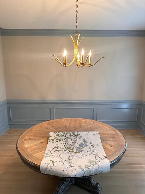 Interior painting project by GW Painting in Charlotte, NC. The image shows a dining room with blue wainscoting, gray walls, and a chandelier.