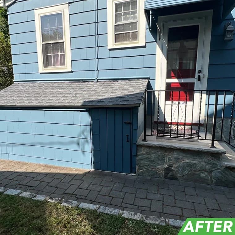 Residential side entry painted in a fresh blue finish with white trim around windows and a red door, completed by Elite Painting and Power Washing, Inc.