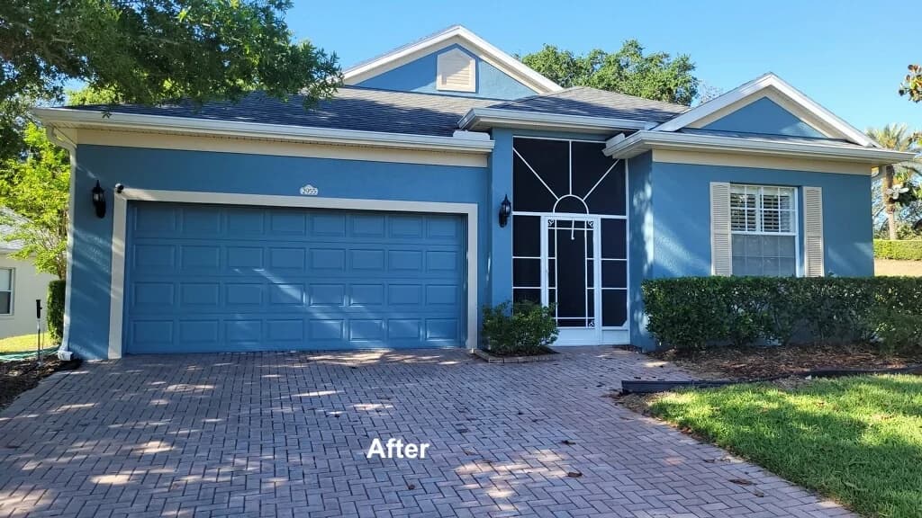This is an image fromJohns Painting And Pressure Washing company, located in Clermont, FL. The image is an after photo of freshly painted blue single-story home with white trim and two-car garage by John's Painting and Pressure Washing