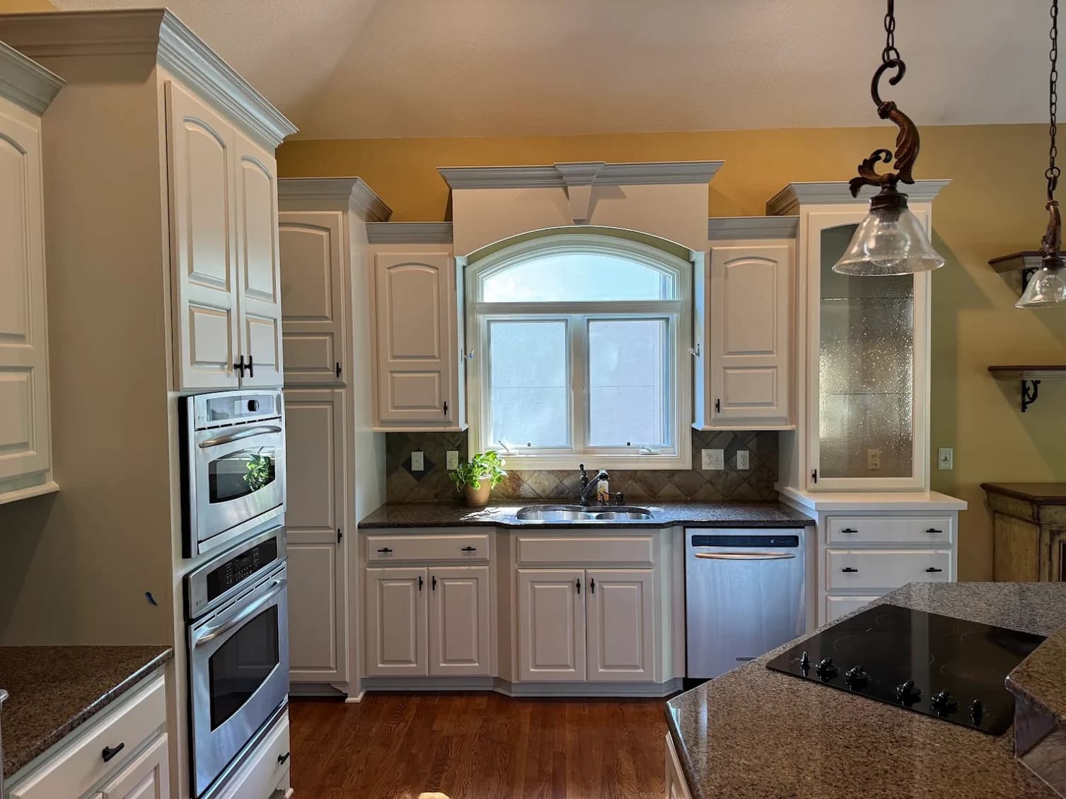 This is an image from Paint Pro Inc. The image is interior kitchen painting in Kansas City KS with freshly painted white cabinets and updated backsplash.