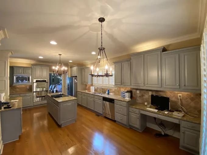 Painting work by Global Painting Pro LLC in Nashville, Tennessee. The image shows a gray kitchen with white cabinets and dark counters.