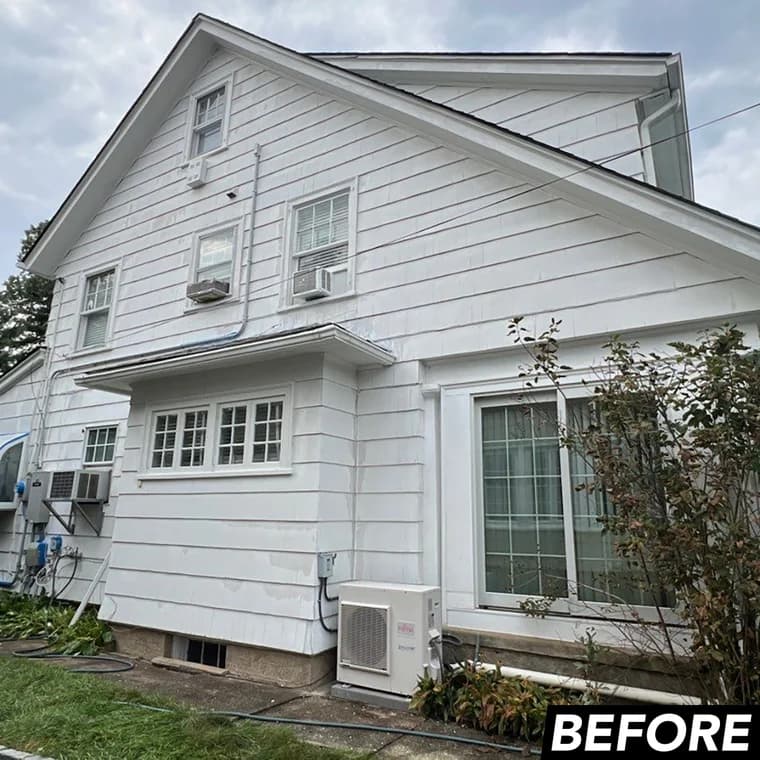 Two-story home shown before painting, with a worn white exterior and visible patching, prepared by Elite Painting and Power Washing, Inc.