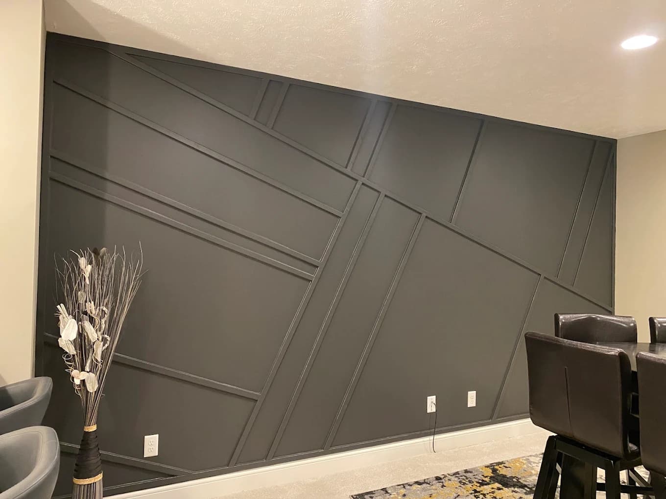 Interior trim painting project by Total Coverage Painting in Bloomington, Illinois. The image shows a dark geometric accent wall with matching panel trim in an entertainment area.