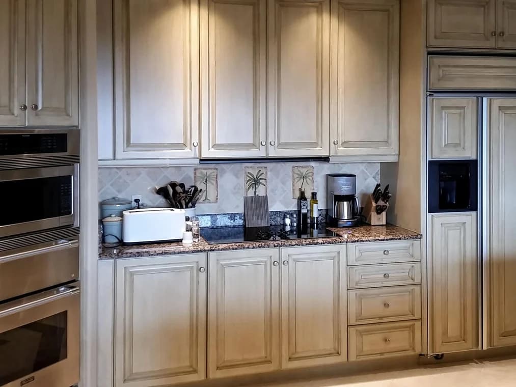 This is an image fromAncient Modern Finishes company, located in Bonita Springs, FL. The image is a traditional kitchen with custom cream-colored cabinets and glazed finish by Ancient Modern Finishes 