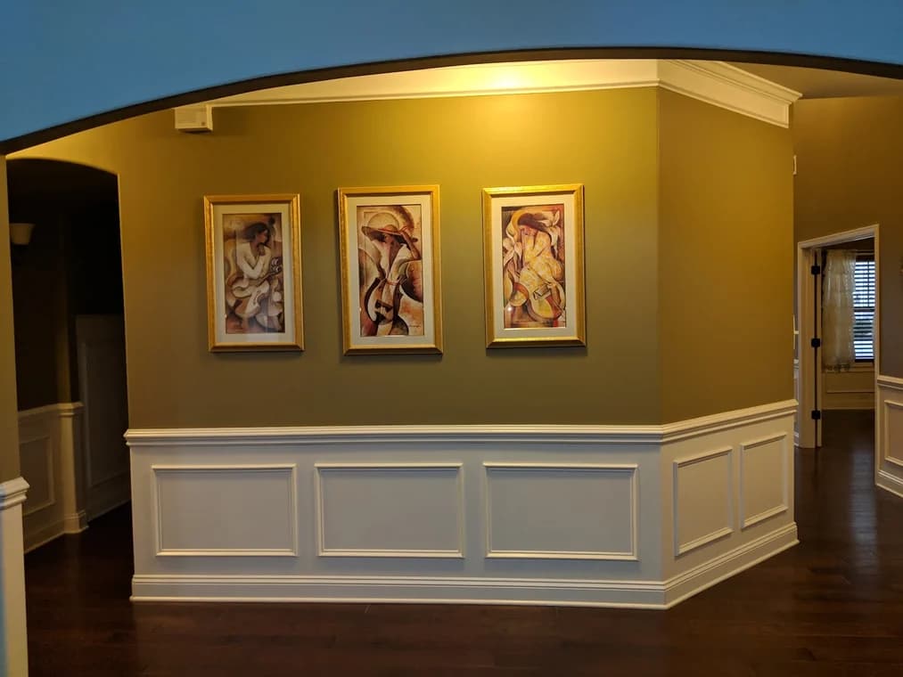 Interior painting project by 360° Painting of Lake Norman in Charlotte, NC. The image shows an olive accent wall with white wainscoting and framed art.
