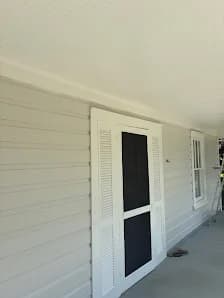 Exterior painting project by Zarazua Painting in Durham, North Carolina. The image shows white siding, a screened door, porch ceiling, and window trim.