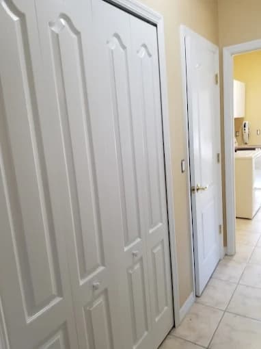 This is an image from Paint Masters Painting Contractors LLC company, located in Venice, FL. The image is a freshly painted white interior doors in a tiled hallway leading to kitchen, completed by Paint Masters Painting Contractors LLC