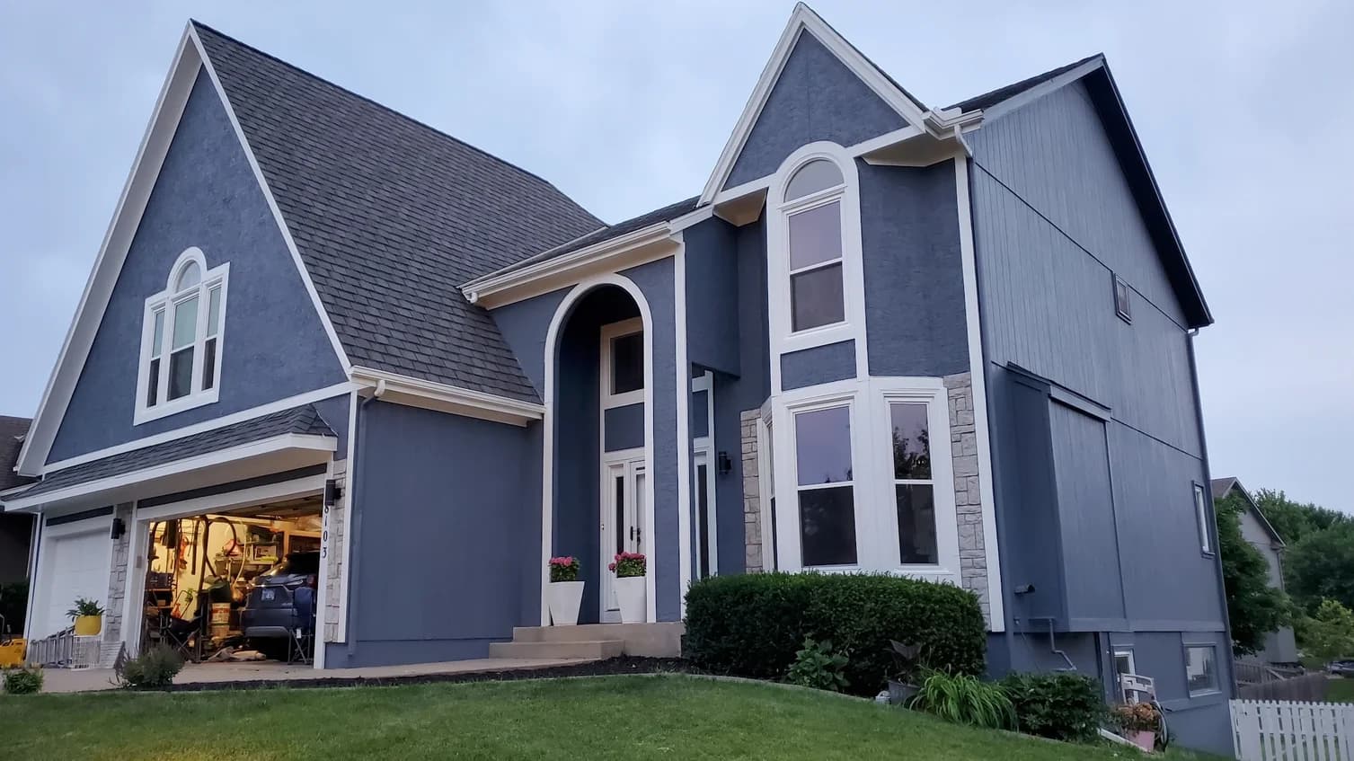 This is an image from Scarlett Painting & Remodeling. The image shows a home exterior painted in a rich blue tone with bright white trim for a crisp, updated look.