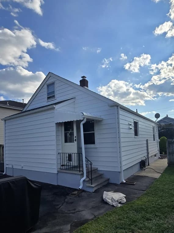 This is an image from That 1 Painter North Jersey. It shows the back view of a freshly painted white home with new siding and trim.
