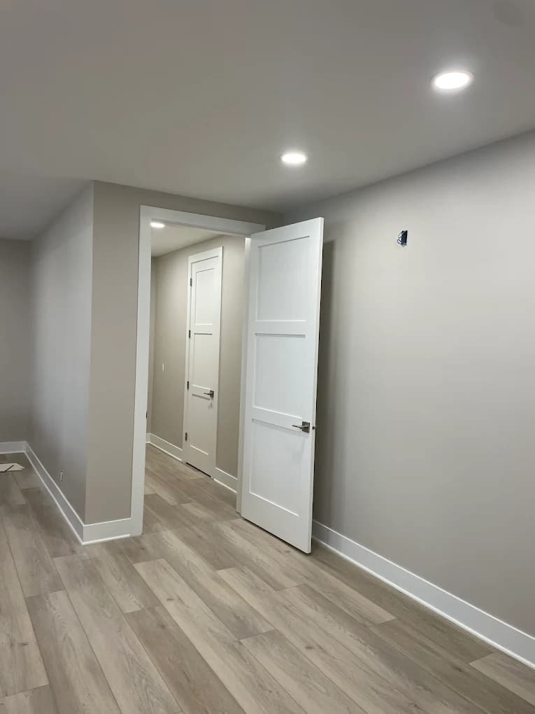 Interior painting project by Michael's Painting Service in Rockford, IL. The image shows a hallway with light gray walls, white trim, recessed lights, and wood-look flooring.