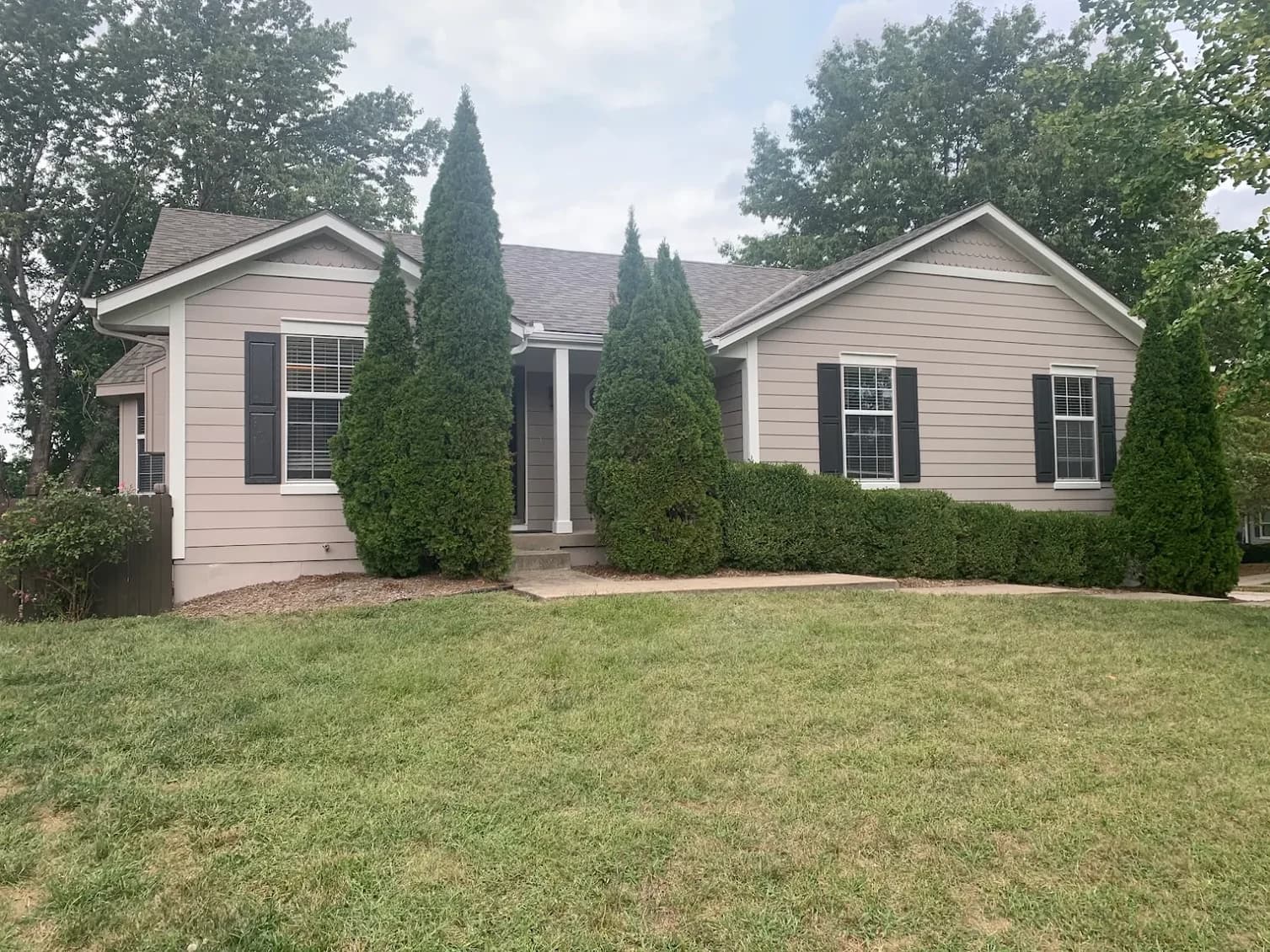 This is an image from Scarlett Painting & Remodeling. The image shows a home exterior with freshly painted light taupe siding and white trim.