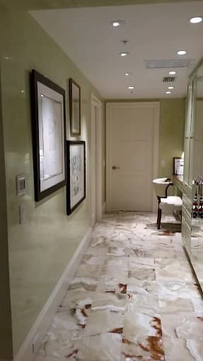 This is an image fromAncient Modern Finishes company, located in Bonita Springs, FL. The image is a hallway with polished marble flooring and light green decorative plaster walls by Ancient Modern Finishes