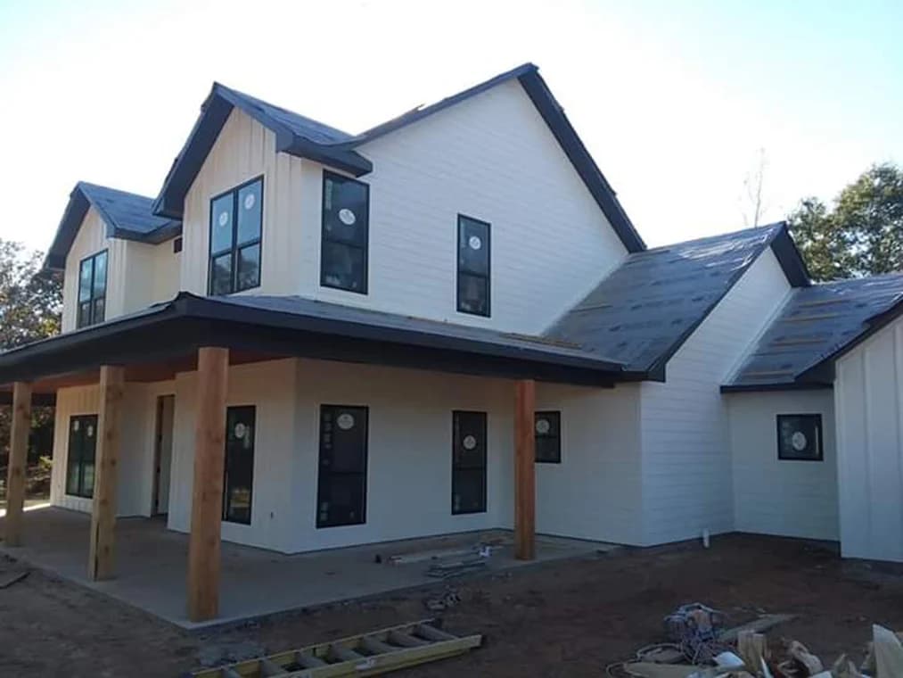 "This is an image from Reeves Painting, located in Texas. The exterior photo shows a two-story home with white siding, dark trim, natural wood posts, and a partially completed roof."