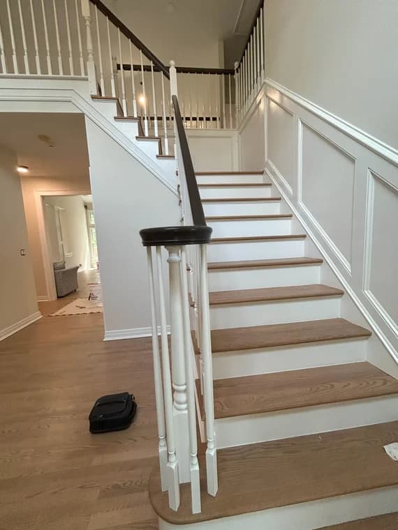 This is an image from Carfagno Professional Painting & Power Washing LLC. It highlights a newly refinished staircase with white risers, wooden steps, and dark handrails.