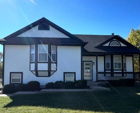 This is an image from Stone Painting. The image shows a white and black split-level home with updated exterior paint and clean trim details.