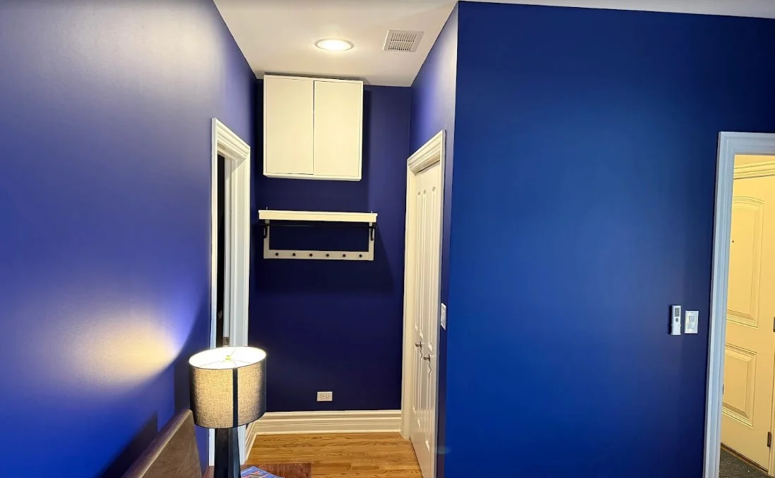 Interior painting by Big League Painting in Glenview, Illinois. The image shows deep blue hallway walls, white trim, and hardwood floors.