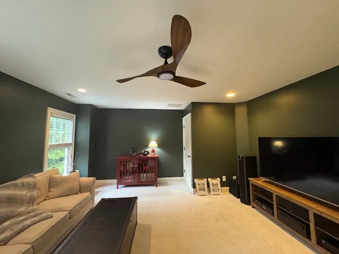 Interior painting project by Matrix Painting Inc. in Raleigh, NC. The image shows a living room with green walls, tan sofas, and wood floors.