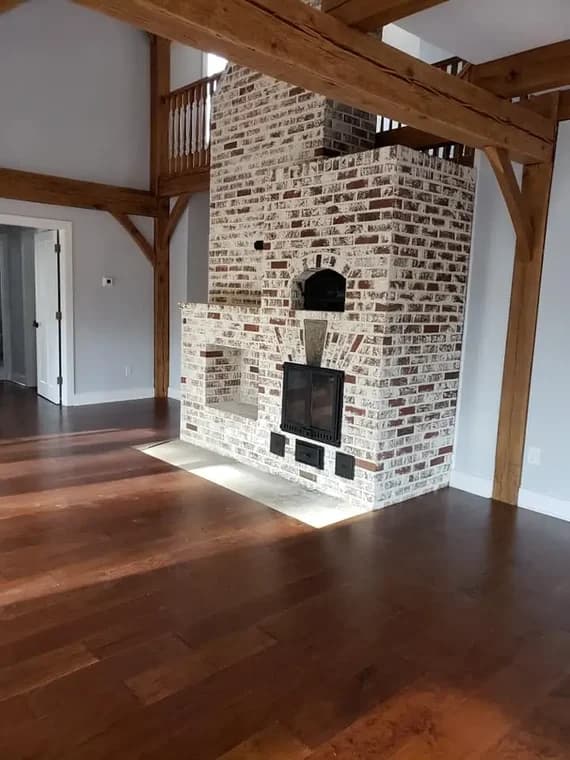 This is an image from Sam Professional Painting LLC, located in Maryland. The interior room features a whitewashed brick fireplace, exposed wood beams, and newly finished hardwood floors.