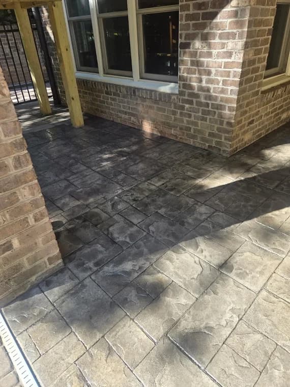 Exterior surface project by Grace Painting & Contractors in Mooresville, NC. The image shows a brick porch with stamped concrete, windows, posts, and shaded walls.