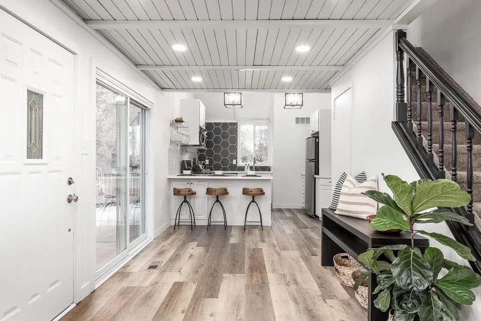 Finished entry and kitchen area with bright painted walls, white ceiling, black railing, and wood-look flooring by Paint EZ of Durham.