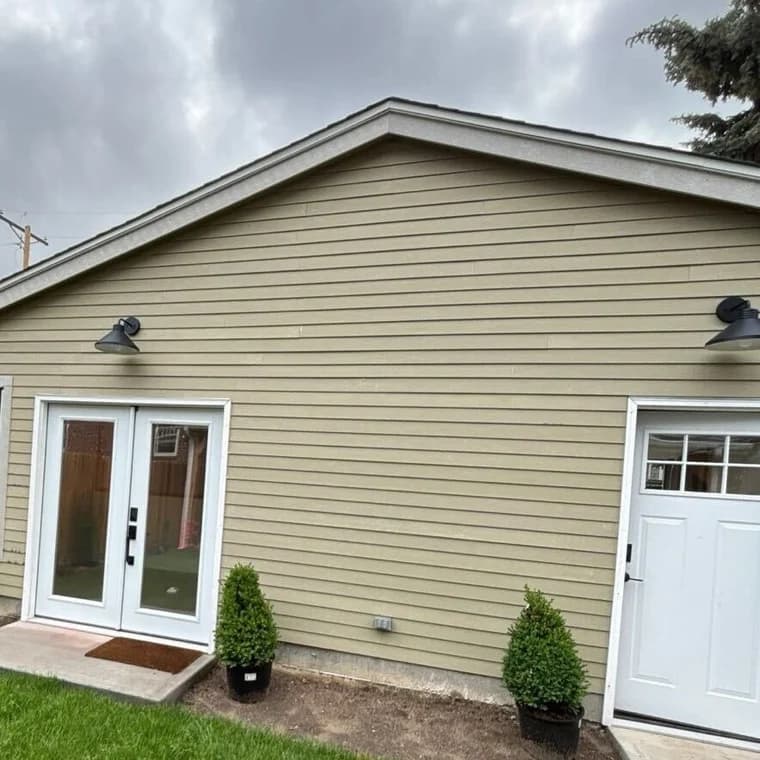 This is an image from Paint Denver company, located in Denver, CO The image is a newly painted beige exterior siding with white trim and double doors, completed by Paint Denver residential painting team
