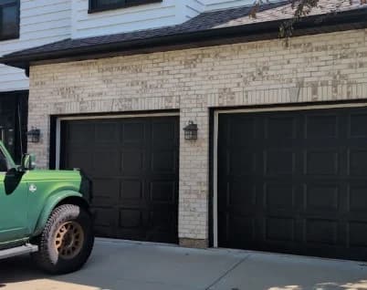 Powers Painting & Decorating, LLC serves Frankfort, Illinois. A garage exterior contrasts black doors and trim with light brick and a clean concrete drive.