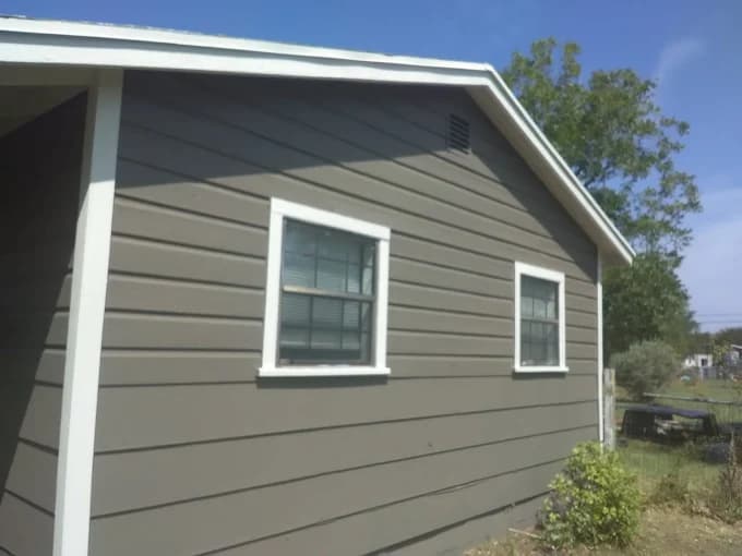 "This is an image from Alvarez Painting, located in Texas. The image shows a freshly painted gray siding exterior with crisp white trim around the windows."