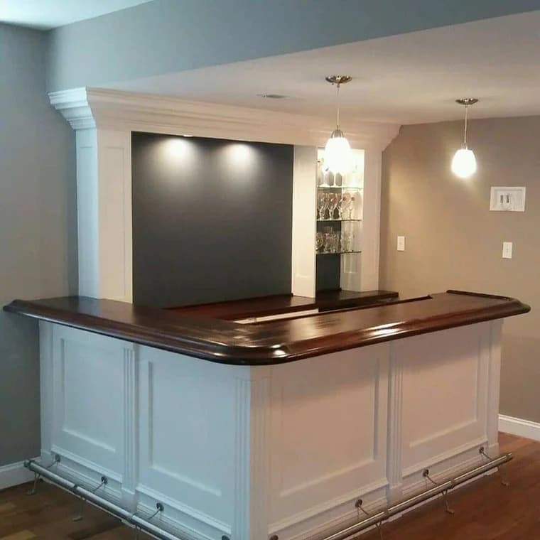 This is an image from Hands On Painters, located in Maryland. The photo shows an indoor bar area with white paneled cabinetry, a dark wood countertop, pendant lighting, and shelving for glassware.