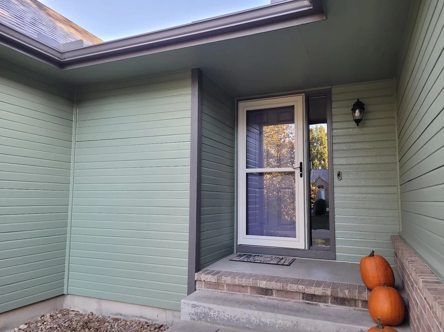 This is an image from Fresh Coat Painters of Wichita.The image shows a freshly painted light green exterior entryway with crisp trim, a clean front door, and smooth siding for a neat, updated curb appeal.