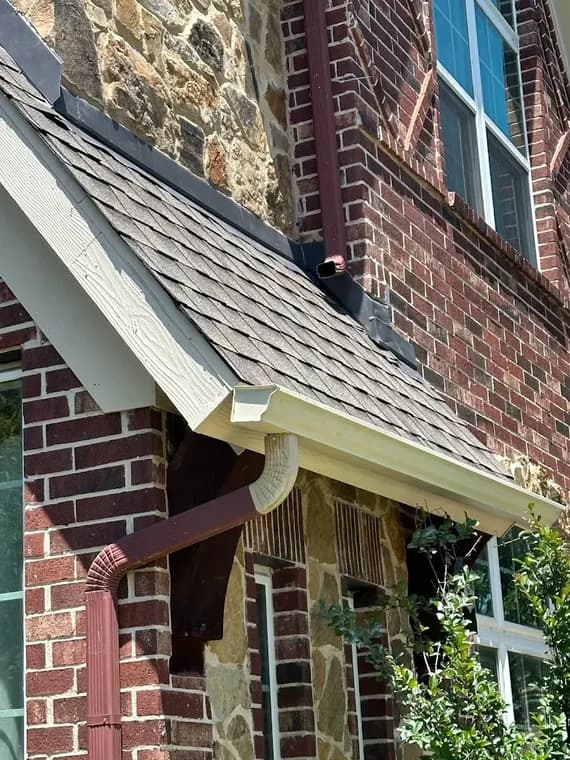 "This is an image from L&D Painting & Remodeling, located in Texas. The picture shows an exterior gutter and downspout installation on a brick home, with contrasting colors between the trim and masonry."