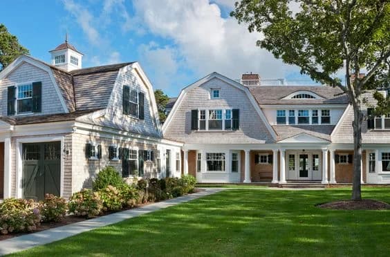 This is an image from Schmidt Painting, located in Massachusetts. It highlights an exterior of a Cape Cod-style home painted by Schmidt Painting, showcasing light-colored siding with dark shutters, white trim, and a well-maintained front lawn.