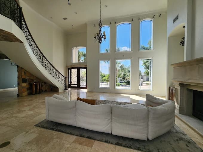 "This is an image from Alvarez Painting, located in Texas. The image shows a spacious living room with tall white walls, large windows, and natural light filling the room."