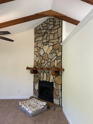 Interior painting project by CertaPro Painters of Salisbury/Concord/Gastonia, NC in Kannapolis, NC. The image shows a room with a stone fireplace, mantel, white walls, and fan.