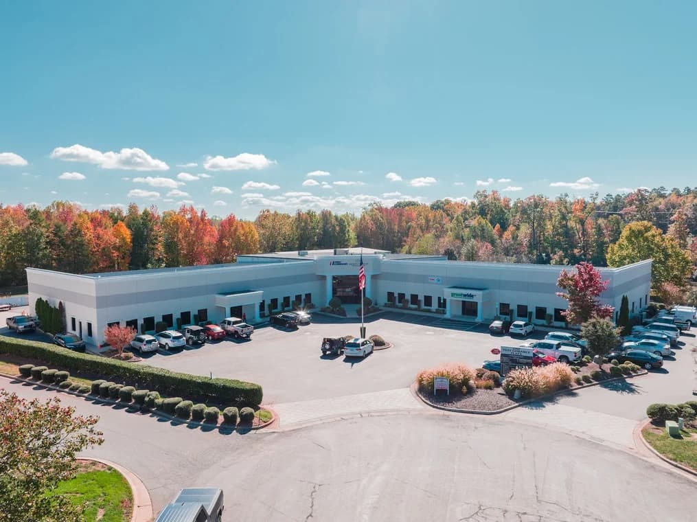 Commercial exterior painting project by Grace Painting & Contractors in Mooresville, NC. The image shows a low office building, parking lot, white facade, and autumn trees.