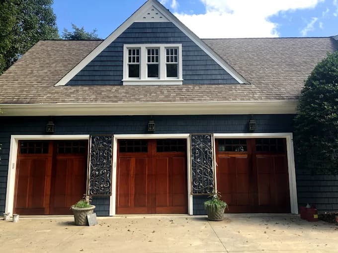 Exterior painting project by Still Perfection Painting Co. in Belews Creek, North Carolina. The image shows blue siding, white trim, and wood garage doors.
