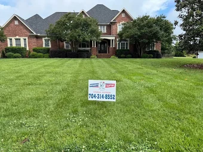 Exterior painting project by Richard's Painting of Concord in Concord, North Carolina. The image shows a brick home, green lawn, and company yard sign.
