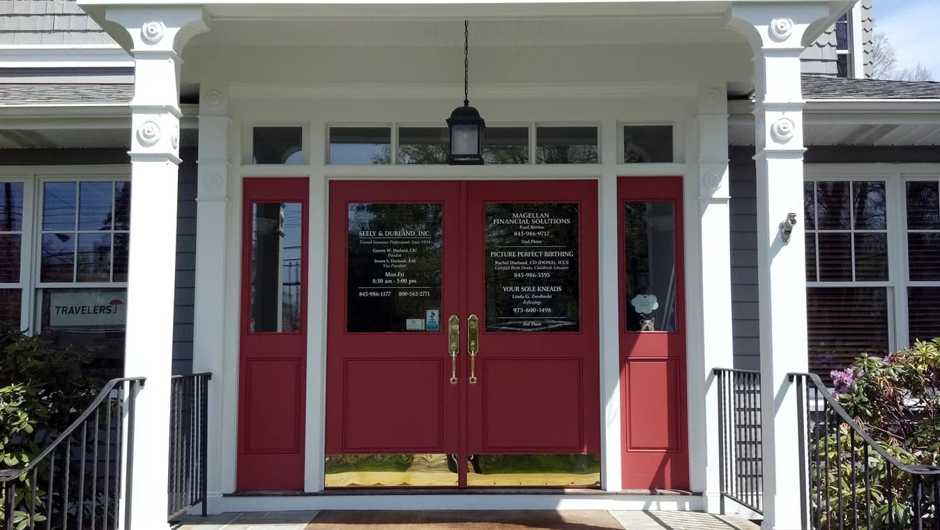 This is an image from CertaPro Painters of Orange County NY, located in New York. The photo shows a commercial building entrance with bright red double doors, white trim, decorative columns, and black railings on each side of the steps.