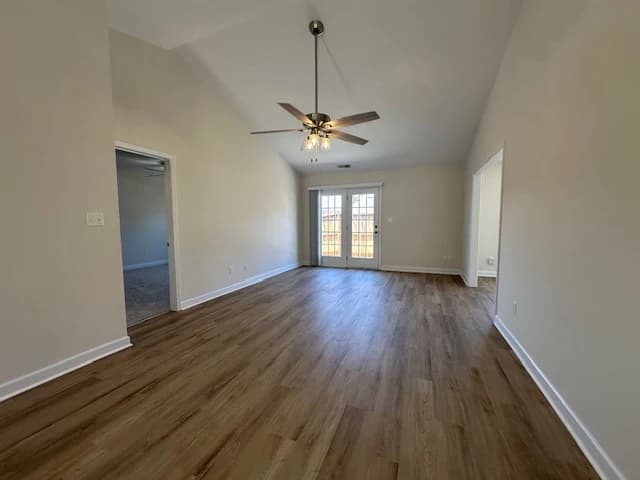 Interior painting project by DIP Coatings in Troutman, NC. The image shows an empty room with light walls, wood floor, ceiling fan, and glass doors.
