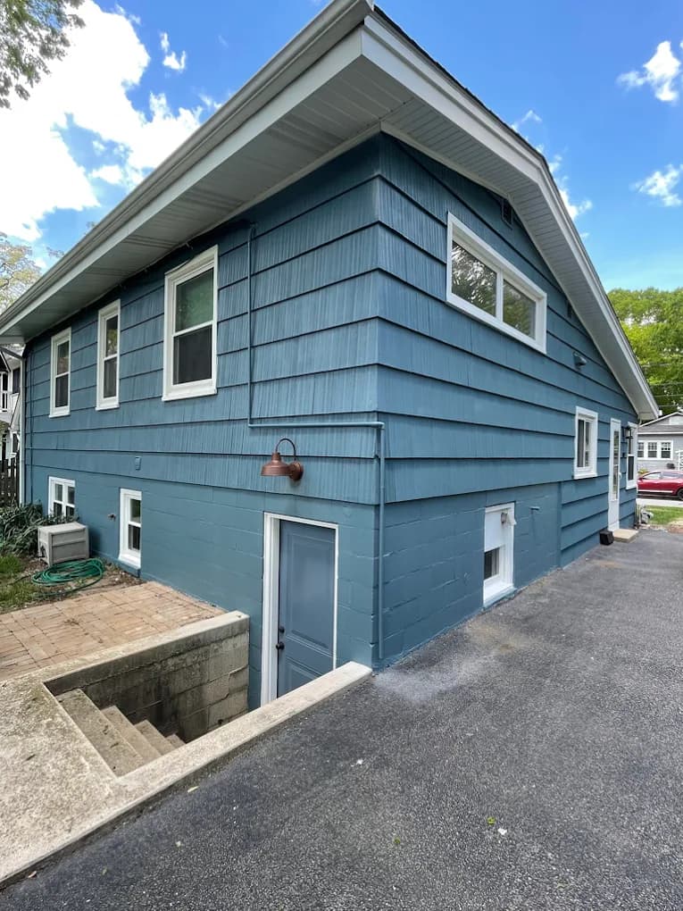Exterior painting by Big League Painting in Glenview, Illinois. The image shows blue siding, white trim, a painted foundation, and a driveway.